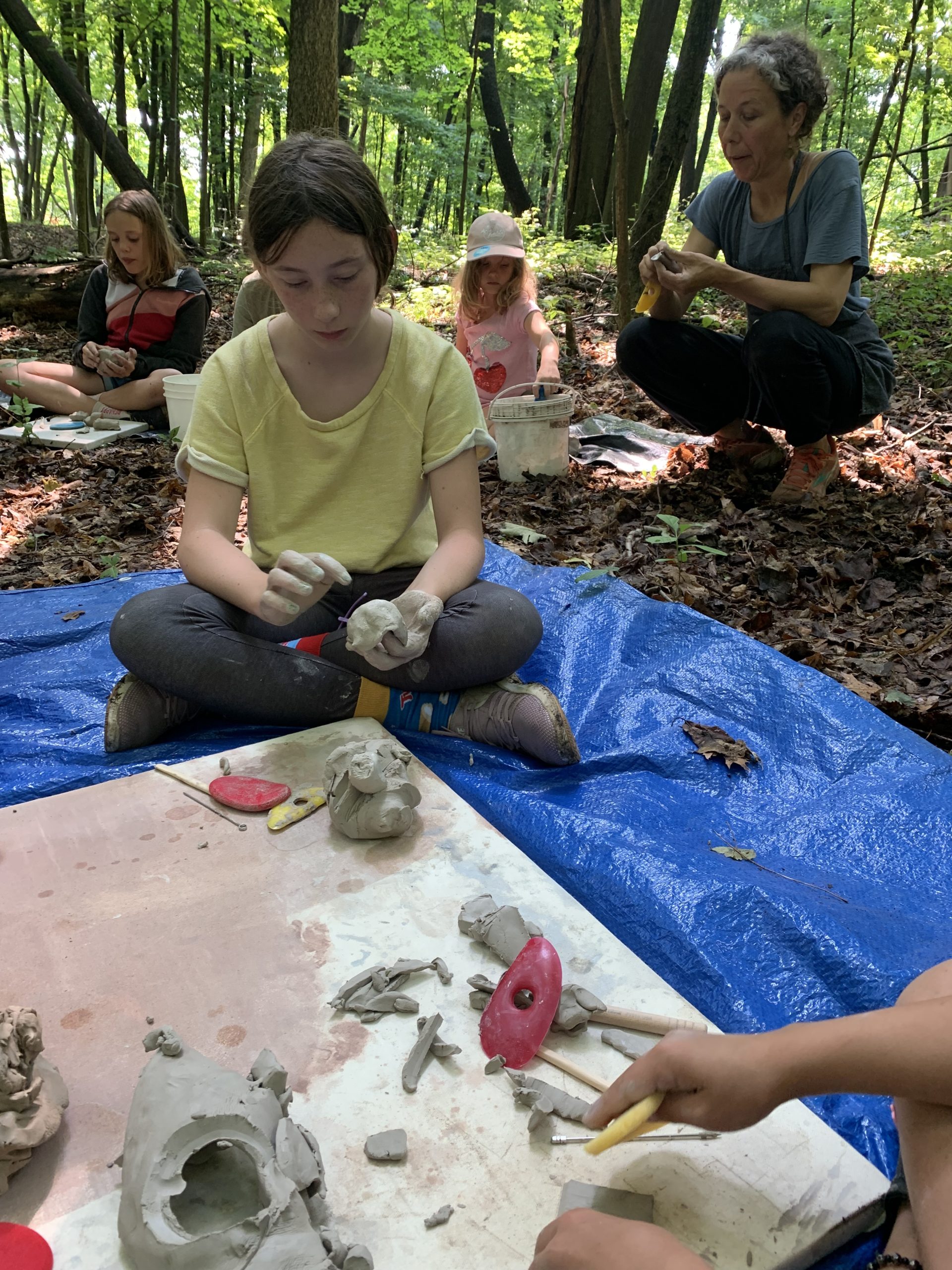 Art educator guiding children at outdoor summer art camp